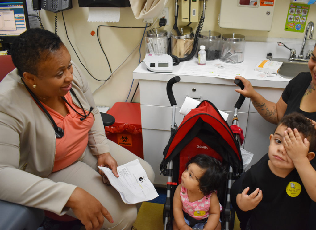 Provider speaking with mother and young patients. Find care.